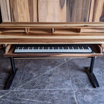 Wooden digital piano  studio deskon a gray floor with wooden wall in the background